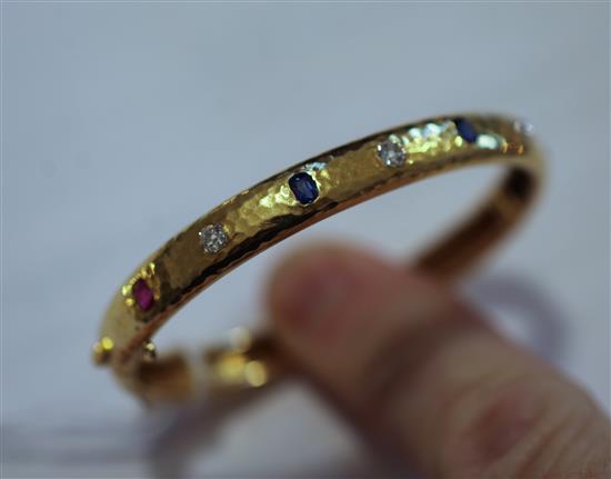 A planished 18ct gold, ruby sapphire and diamond hinged bangle, gross weight 20.4 grams.